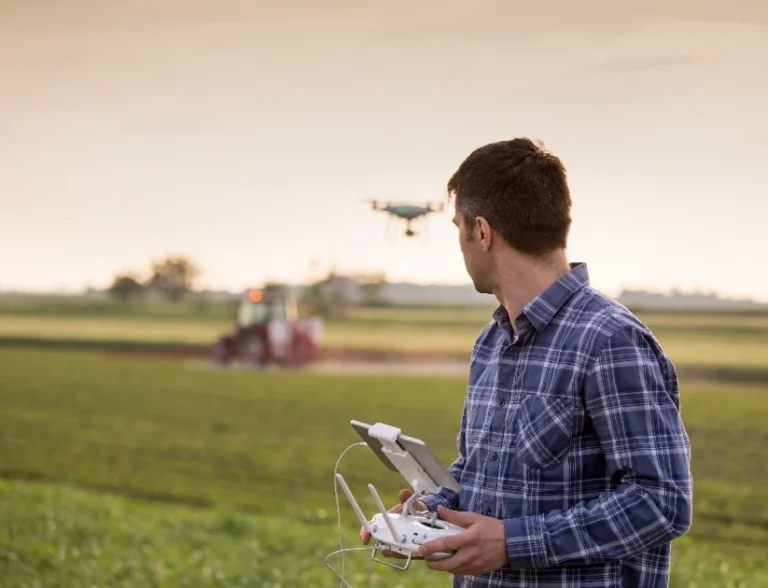 ere’s an SEO-optimized ALT text for the image you described:
"Man operating a drone over a farm field, showcasing smart agriculture and tech-driven plant-based cultivation practices.