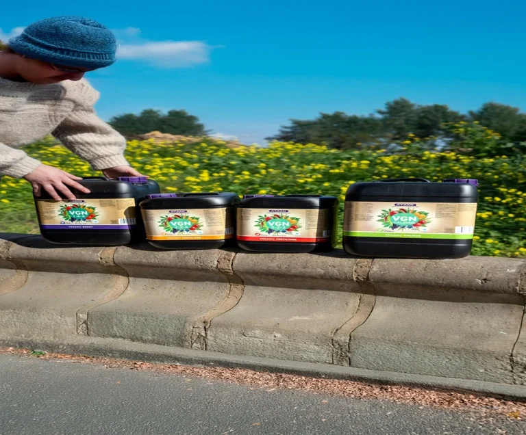 Man displaying Atami VGN jerrycans in a row, showcasing organic liquid nutrients for sustainable plant cultivation.