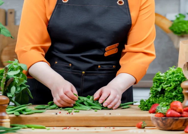 Person preparing fresh vegetables on a cutting board at a table, promoting homegrown high-protein crops and healthy eating.